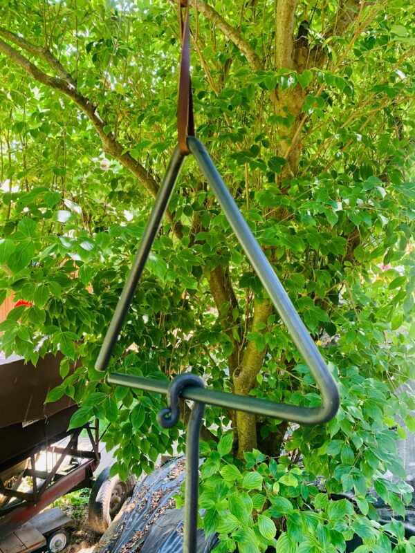 Handcrafted blacksmith-made dinner bell hanging outdoors, showcasing rustic charm and durable craftsmanship.