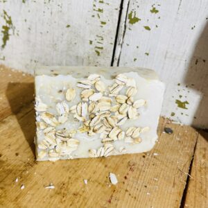 Handmade calming oatmeal soap with goat milk and tallow, on a rustic wooden surface.