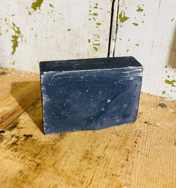 Deep cleansing soap bar with charcoal and peppermint essential oil, against a rustic background.