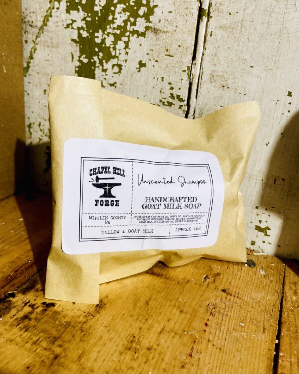 A goat milk shampoo bar made with tallow, displayed against a rustic wooden background.