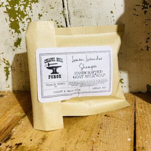 A bar of hair growth shampoo with goat milk, tallow, and lemon and lavender essential oils, displayed against a rustic background.