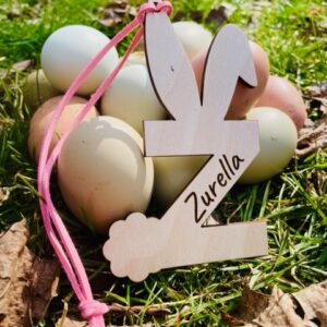 Personalized Easter Basket Tags sitting in the grass next to real easter eggs. Easter basket tags for Easter baskets.