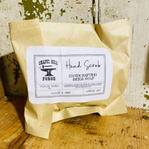 Natural hand soap bar with locally crafted beer, lemon, and orange essential oils, on rustic wooden background.