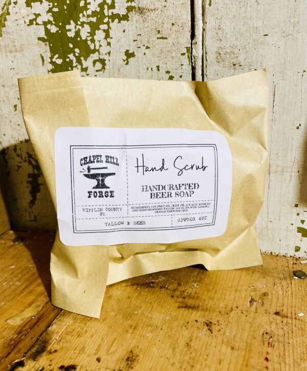 Natural hand soap bar with locally crafted beer, lemon, and orange essential oils, on rustic wooden background.