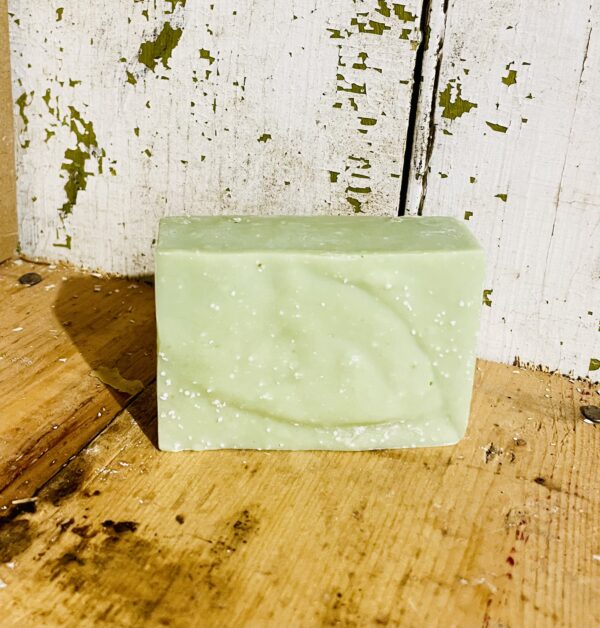 A bar of detox soap with French green clay, mint, and lavender essential oils, resting on a wooden surface.