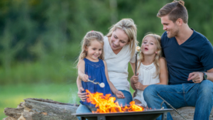 A family gathered around a campfire, using a personalized campfire poker to adjust burning logs and enjoy outdoor bonding time