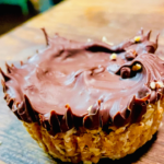 Homemade healthy peanut butter cups with a dark chocolate coating and a creamy peanut butter filling, displayed on a wooden butcher block.