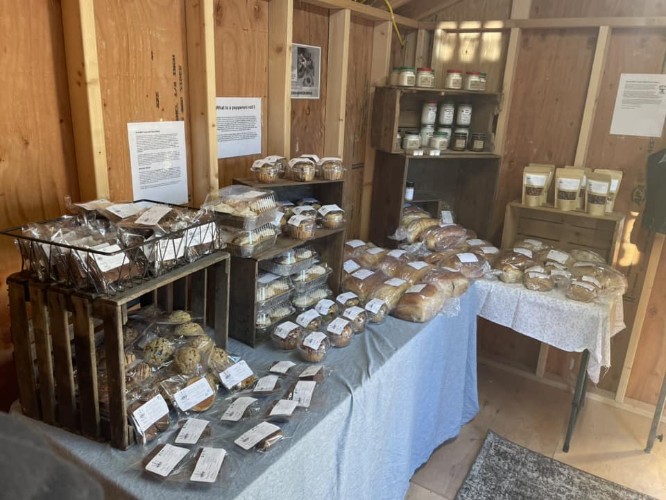A table in the Bread Shed at Beaver Springs, showcasing an array of freshly baked breads, cinnamon rolls, and sweet treats.