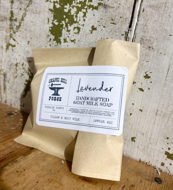 Handcrafted calming lavender goat milk soap bar in a simple brown paper bag, topped with dried lavender buds