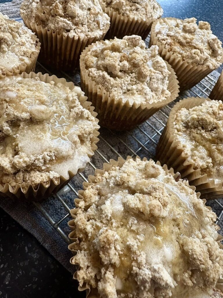 A tray of tall, golden bakery-style muffins with buttery crumb topping, freshly baked in bulk — made using our signature microbakery sourdough muffin recipe.